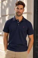 Chomba azul marino de manga corta, con cuello tipo polo y tapeta con tres botones. Cuenta con un pequeño bordado rojo en el pecho.