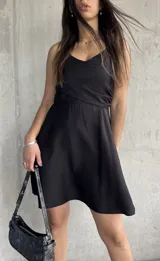 Vestido corto negro con breteles finos y escote cruzado.