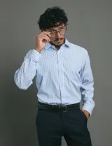 Camisa de vestir de manga larga con diseño de rayas verticales en tonos blanco y celeste. Presenta cuello clásico, cierre frontal con botones y un bolsillo en el pecho.