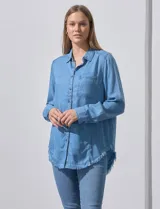 Camisa celeste de tencel, marca Hester & Orchand. Tiene cuello con solapa, escote en V, abertura central con botones, bolsillo aplicado en el frente y ruedo desflecado.