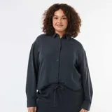 Blusa fluida de manga larga en color azul oscuro, con cuello camisero clásico y cierre frontal de botones a tono.
