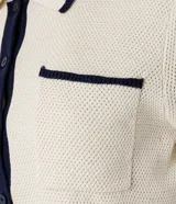 Blusa color crema con cuello inglés y detalles en azul marino, de punto más sostenible, en modelo comfort. Posee cuello inglés, manga corta, abotonado delantero, bolsillo y detalles contrastantes.