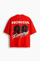 Remera de malla color rojo, con cuello en V, mangas cortas y corte oversized. Cuenta con diseño estampado frontal de Honda con banderas a cuadros y el logo de la marca.