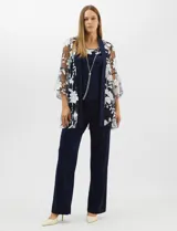 Conjunto de tres piezas compuesto por una musculosa de silueta recta, un pantalón de seda fría con caída fluida y cintura elastizada, y un kimono de tul con bordado floral, frente abierto y mangas acampanadas. Incluye collar largo removible.