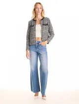 Chaqueta de tweed en tonos blanco y negro, con cuello redondo y abertura frontal. Presenta detalles de cinta con cadena en el cuello y en los bolsillos delanteros. Con forro interno.