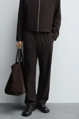 Pantalón regular fit color marrón oscuro, confeccionado en tejido con viscosa. Cuenta con cintura elástica, bolsillos delanteros y detalle de bolsillos traseros de vivo. El cierre frontal es con cremallera y botón.