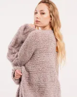 Buzo tejido a mano con lana, color rosa con motas de colores. Diseño oversized, largo entre la cintura y la cadera, con detalle de trenzas en las mangas.