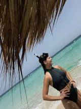 Top marrón con cuello halter, cierre frontal con cremallera amarilla y ribete blanco.