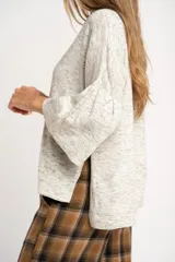 Sweater de punto con efecto jaspeado, de corte oversize, cuello redondo y mangas largas con terminación acampanada tipo volado.