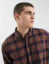 Camisa de franela a cuadros con cuello button-down, manga larga y botones de madera. Presenta dos bolsillos tipo parche en el frente con cierre de botón.