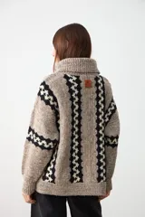 Sweater de punto grueso con cuello tortuga, diseño de rayas verticales con patrón geométrico en contraste, manga larga y corte holgado.