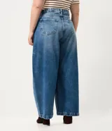Pantalón de jean azul con lavado medio, corte barrel de piernas amplias, cintura con pasacintos, bolsillos funcionales y pinzas en las piernas.
