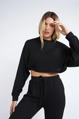 Buzo corto de tejido rib en color verde militar, con mangas largas y cuello redondo. Presenta un diseño holgado y cropped.