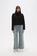 Buzo de cuello alto tipo polera, color verde oliva, con corte holgado, mangas largas y un bolsillo frontal aplicado en el pecho.