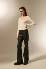 Pantalon de eco-cuero negro, de corte flare con costuras verticales frontales y detalle de tajo en el ruedo.