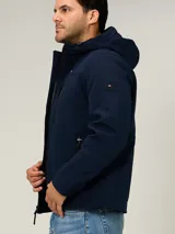 Campera soft shell Tommy Hilfiger color azul marino, con capucha, cierre frontal de cremallera con detalles tricolores y bolsillos con cierre en los laterales y en el pecho.