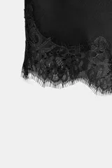 Falda corta de tiro medio confeccionada en tejido satinado negro, con bajo asimétrico y aplicación de encaje a tono.