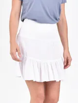 Falda corta de color negro, con cintura elástica tipo nido de abeja y ruedo con volado.