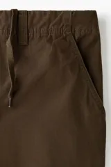 Pantalón cargo de lona de algodón con bolsillos laterales tipo cargo, bolsillos traseros con solapa y pliegues en las rodillas. Presenta cierre con botón y ajuste en la cintura.