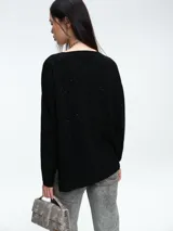 Sweater de punto gris con escote en V profundo, hombros caídos y mangas largas. Presenta un diseño de calce relajado con sutiles micro lentejuelas integradas en el tejido.