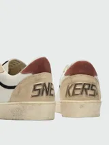 Zapatillas Ball Star de Golden Goose confeccionadas en cuero blanco, con puntera y refuerzo trasero de gamuza en tono beige, estrella lateral laminada en tono dorado y cordones negros.