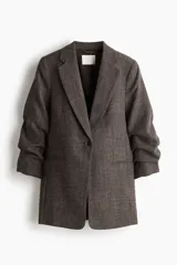 Blazer largo de botonadura sencilla con solapas de muesca, hombreras, pinzas en la cintura y bolsillos delanteros ribeteados. Presenta mangas tres cuartos con diseño remangado y forro interior.