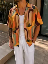Camisa de manga corta de fibrana con estampado abstracto multicolor en tonos naranja, marrón, verde y beige, de corte recto y cierre frontal con botones.