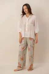 Pantalón fluido de tiro alto en color crudo con estampado floral en tonos naranjas y detalles de franjas laterales en azul marino.