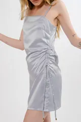 Vestido corto color borgoña, con breteles finos, escote recto y drapeado lateral con cordones ajustables.