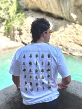 Remera blanca de algodón con cuello redondo y estampado en la espalda con imágenes de cogollos de marihuana y texto "BROKERS HIGH QUALITY GOODS".