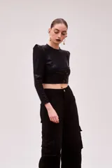 Remera crop negra metalizada de lycra, con mangas largas y hombreras.