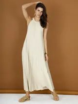Vestido largo color crema de lurex plisado, con cuello halter y corte recto.