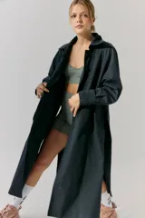 Trench midi color negro, confeccionado en mezcla de algodón y nylon con acabado repelente al agua. Presenta diseño con tajos laterales, bolsillos internos y etiqueta de marca en la espalda.