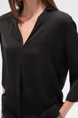 Blusa de poliéster color negro, con cuello en V, corte holgado y mangas tres cuartos.
