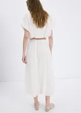 Falda midi evasé de color blanco, confeccionada en algodón con detalles bordados tonales, cintura elástica y forro interior.