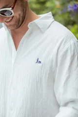 Camisa blanca de manga larga con cuello clásico y botones frontales.