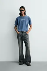 Camiseta relaxed fit de color azul con efecto lavado, cuello redondo y manga corta. Cuenta con un estampado de texto a contraste en el delantero y acabados con efecto rotos.