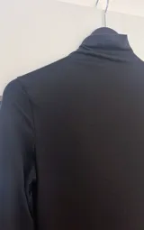 Vestido corto negro de mangas largas y cuello alto.