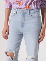 Jeans recto de tiro medio, color celeste claro, con roturas en las rodillas.