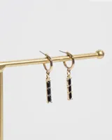 Aros dorados cortos con dije colgante con tres piedras negras baguette.