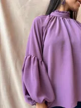 Blusa verde con cuello alto fruncido y mangas largas abullonadas.