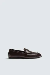 Mocasín de vestir en piel color marrón oscuro, con detalle de antifaz en el empeine, horma redonda y suela de goma Vibram.
