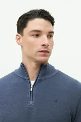 Buzo azul de felpa con medio cierre frontal, cuello alto y logo de goma en el pecho.