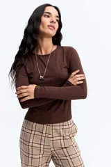 Remera de manga larga ajustada al cuerpo, confeccionada en tejido elástico de poliéster y spándex, con cuello redondo clásico.