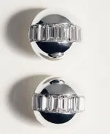 Aros de diseño circular con acabado metálico plateado y detalle de cristales incrustados en el centro.