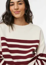 Buzo de tejido de punto con diseño de rayas horizontales en color bordeaux y crema, cuello redondo y mangas largas con puños acanalados.