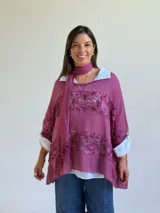 Sweater de punto magenta con diseño holgado, cuello redondo y detalles de encaje floral aplicado en el frente. Incluye una bufanda tipo choker integrada del mismo tejido.
