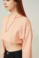 Buzo color durazno, corto, con capucha y mangas largas.