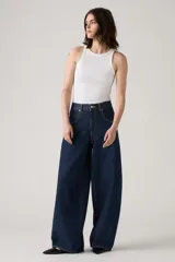 Jean de corte baggy y silueta barrel, confeccionado en denim rígido de color azul oscuro. Presenta costuras laterales curvadas que definen su forma característica, tiro alto y cierre frontal con botón y cremallera.