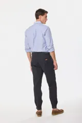 Pantalón de vestir color verde oliva, de corte recto, con bolsillos laterales y traseros. Se ajusta a la cintura con cinturón de cuero marrón.